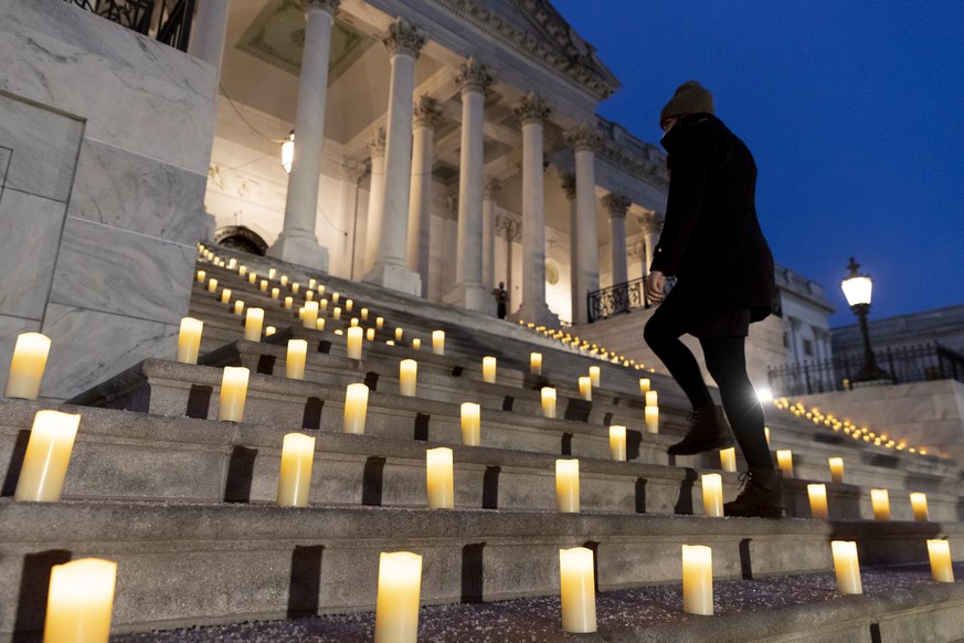 epa09670916 A Congressional staffer in the office of US Speaker of the House Nancy Pelosi walks up the East Front steps of the US Capitol just before a prayer vigil to mark the one-year anniversary of ...