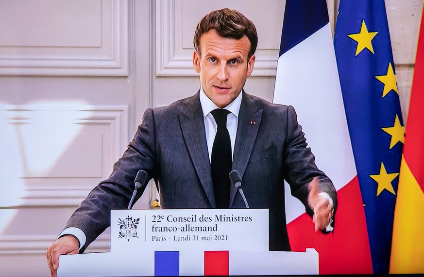 epa09239553 French President Emmanuel Macron on a screen during a joint press conference following a virtual plenary session of the 22nd German-French Ministerial Council, in Berlin, Germany, 31 May 2 ...