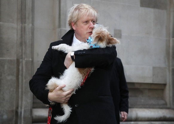 FILE - Britain&#039;s Prime Minister and Conservative Party leader Boris Johnson holds his dog Dilyn as he leaves after voting in the general election at Methodist Central Hall, Westminster, London, T ...
