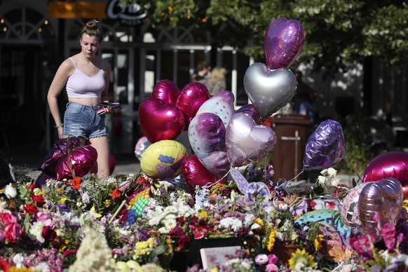 A woman looks at floral tributes that are left the Atkinson art centre in Southport, England, Sunday, Aug. 11, 2024 after three young girls were killed in a knife attack at a Taylor Swift-themed holid ...