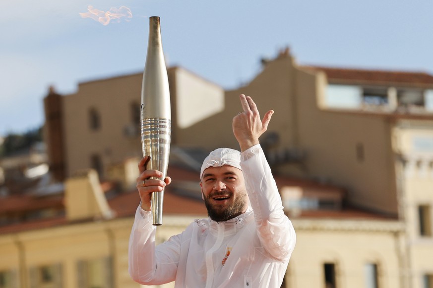 French rap artist Jul holds the Olympic torch during the torch arrival ceremony in Marseille, southern France, Wednesday May 8, 2024. After leaving Marseille, a vast relay route is undertaken before t ...