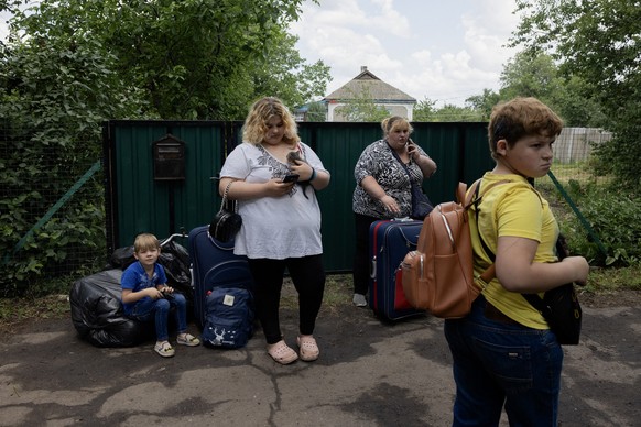 A family with their belongings wait for an evacuation bus in Mezhova, in Dnipropetrovsk Region on June 17, 2025, amid the Russian invasion of Ukraine. (Photo by Tetiana DZHAFAROVA / AFP)