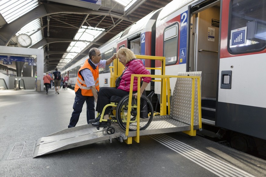 An SBB (Swiss Federal Railways) employee uses a lifting platform to help a woman in a wheelchair get off a train at Zurich Main Station, Switzerland, pictured on August 28, 2014. (KEYSTONE/Gaetan Ball ...