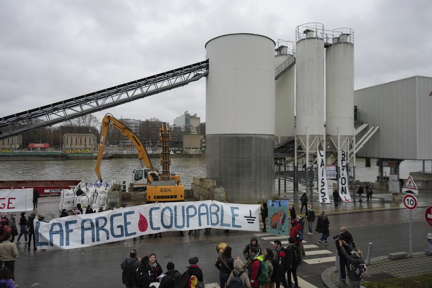 Activists of the environmental group Extinction Rebellion hold a banner reading &quot;Lafarge guilty&quot; outside the Cemex cement plant sits in Paris, Sunday, Dec. 10, 2023. (AP Photo/Thibault Camus ...