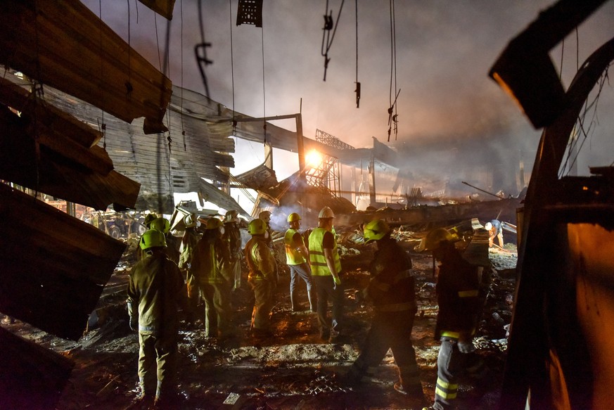 epa10037561 Firefighters and rescue workers clean the rubble of destroyed Amstor shopping mall in Kremenchuk, Poltava Oblast, Ukraine, 27 June 2022. At least eleven bodies were found dead at the scene ...