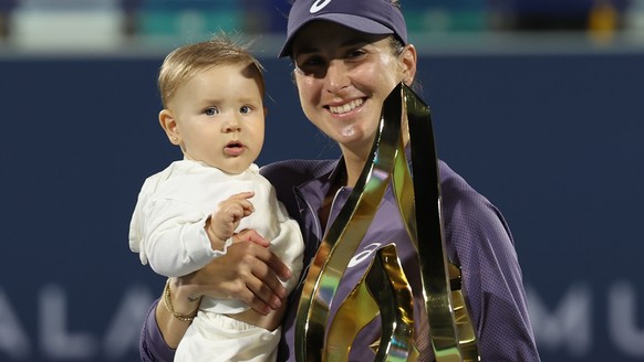 epa11882918 Belinda Bencic of Switzerland carries her daughter while posing with the trophy after winning her final match against Ashlyn Krueger of the USA at the WTA Abu Dhabi Open tennis tournament  ...