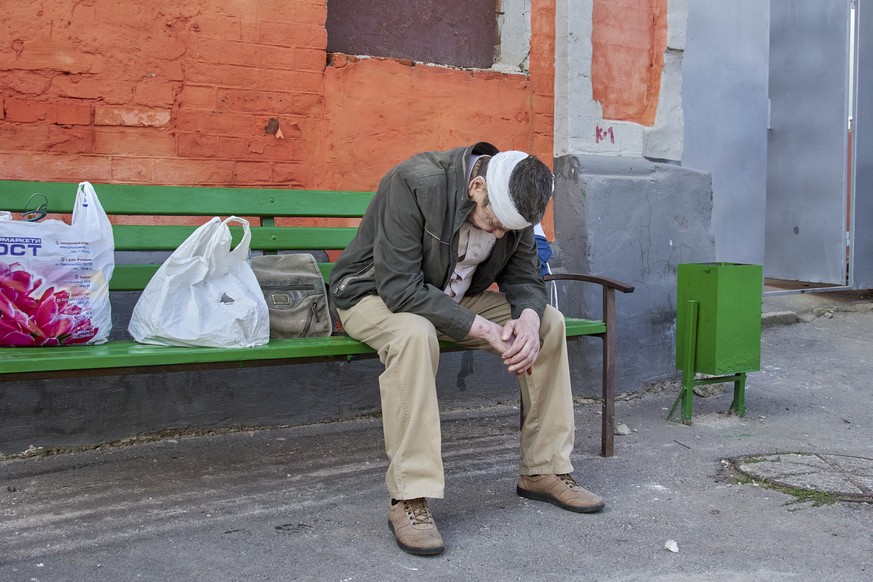 epa10087926 An injured man sits on a bench after shelling hit a residential area in Kharkiv, northeastern Ukraine, 23 July 2022. One person was injured after shelling hit civilian infrastructure in Kh ...