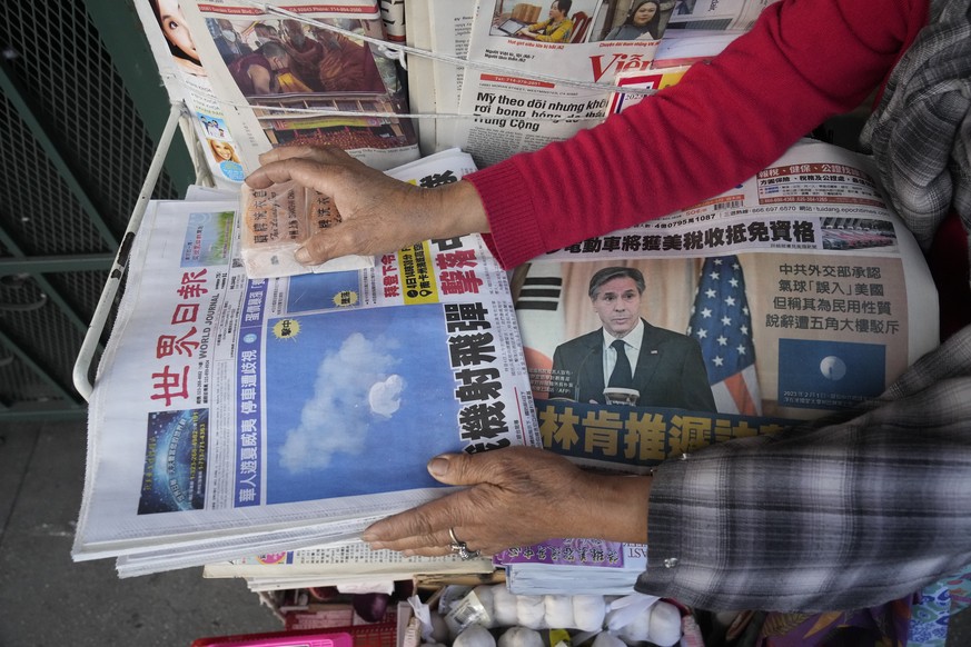 Business owner &quot;Annie&quot; weights down copies of the Chinese Daily News newspaper showcasing pictures of a suspected Chinese spy balloon, in the Chinatown district of Los Angeles Sunday, Feb. 5 ...