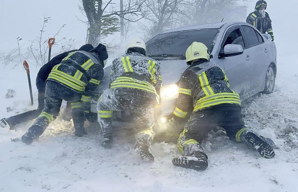 In this photo provided by the Ukrainian Emergency Service, Ukrainian Emergency workers try to push a car trapped in snow on the Odesa region highway, Ukraine, Monday, Nov. 27, 2023. Heavy snowfalls an ...