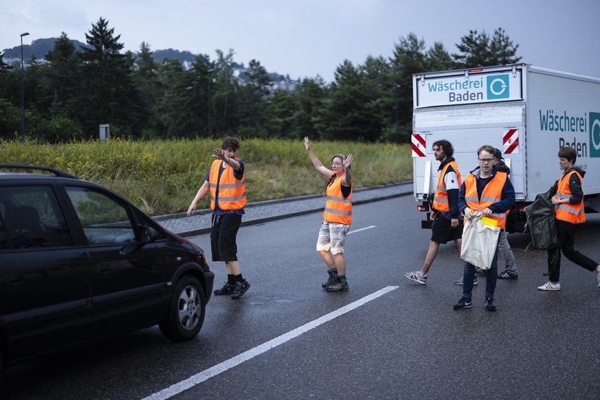 Environmental activists of Renovate Switzerland stop vehicles to sit down on the road during a roadblock action on the motorway A1 exit in Zuerich, Switzerland on June 19, 2023. (KEYSTONE/Michael Buho ...