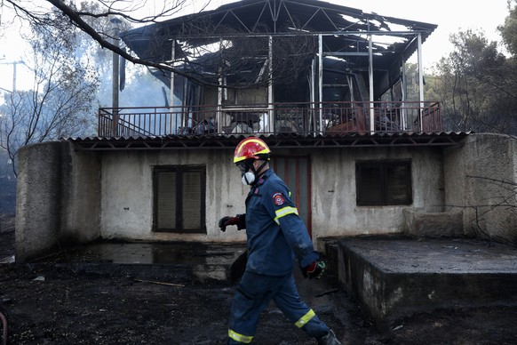 epaselect epa12213802 A firefighter walks past a burned house after a wildfire swept through Pikermi suburb, east of Athens, Greece, 03 July 2025. More than 100 firefighters have been mobilized, along ...