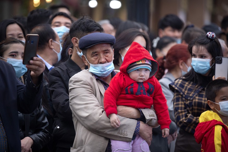 FILE - A man holds a child as they watch a dance performance at the International Grand Bazaar in Urumqi in western China&#039;s Xinjiang Uyghur Autonomous Region on April 21, 2021. Allegations of hum ...