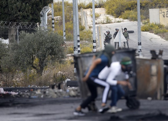 epa10929138 Palestinians (front) run for cover during clashes with Israeli troops at the northern entrance of the West Bank city of Ramallah, near the Israeli settlement of Beit El, 20 October 2023. A ...