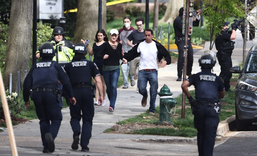 Suite à la fusillade, des gens sont escortés par la police pour se mettre en lieu sûr.