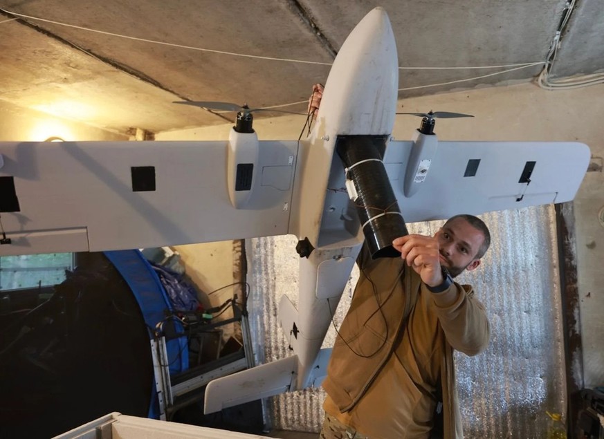 Un soldat ukrainien présente un drone à ailes conçu pour larguer une bombe.