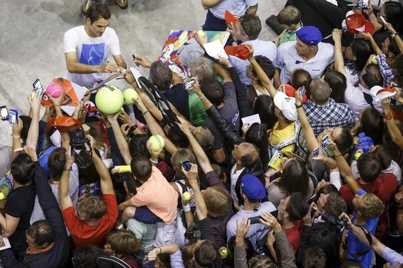 Roger Federer, of Switzerland, signs autographs to his fans after a training session of the Swiss Davis Cup Team prior to the Davis Cup World Group Semifinal match between Switzerland and Italy, at Pa ...