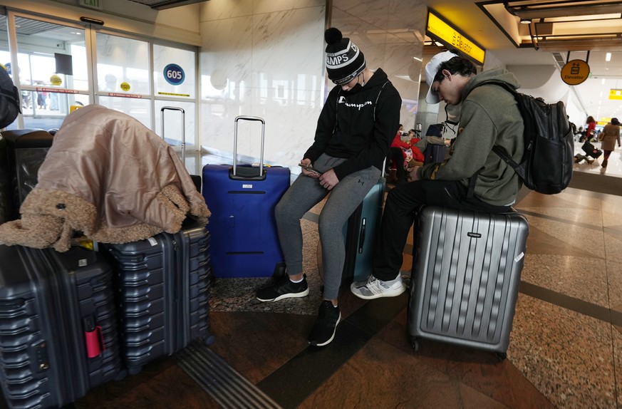 Travelers use their baggage for seats near the Southwest Airlines baggage carousels in Denver International Airport, Sunday, Dec. 26, 2021, in Denver. Airlines canceled hundreds of flights Sunday, cit ...