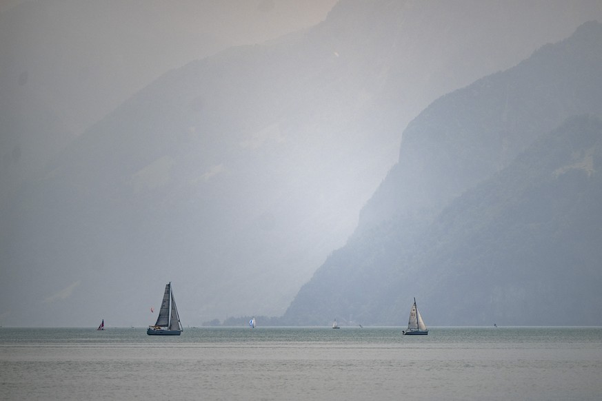 epa12169917 A haze of smoke from Canadian wildfires blankets the sky and mountains at the Urnersee in Brunnen, Switzerland, 11 June 2025. The smoke, originating from wildfires in the Canadian Manitoba ...