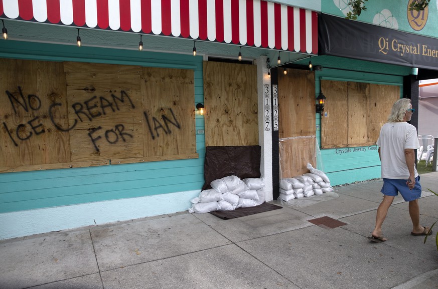 epa10208368 A person walks near an ice cream shop covered with plywood as a preparation for the hurricane Ian in Gulfport, Florida, USA, 26 September 2022. A hurricane warning and storm surge was issu ...