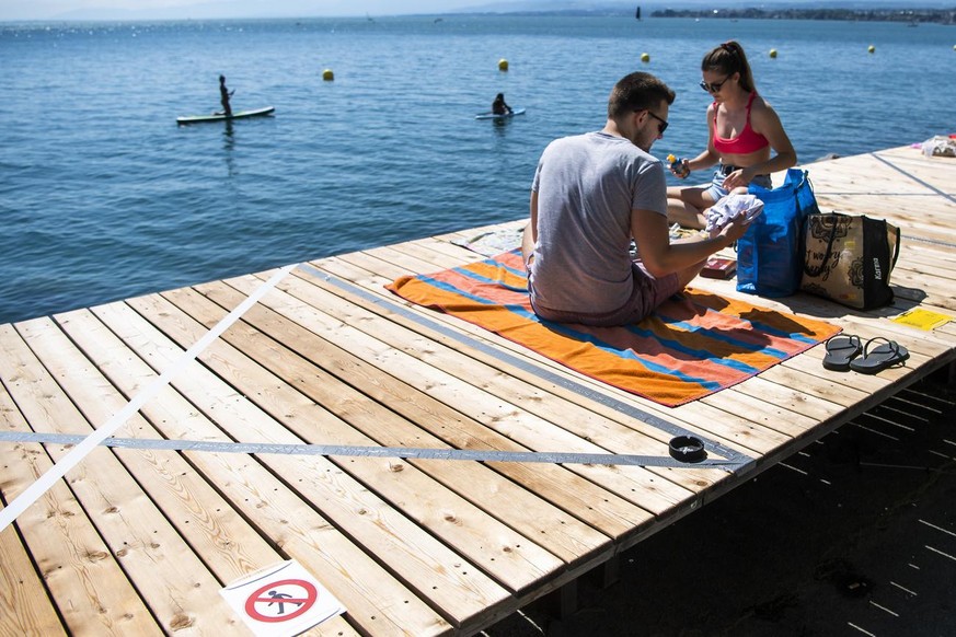 Une separation de distance est visible entre des personnes profitant du soleil sur le deck de la &quot;Jetee de la Compagnie&quot; au bord du lac Leman lors de la crise du Coronavirus (Covid-19) le di ...