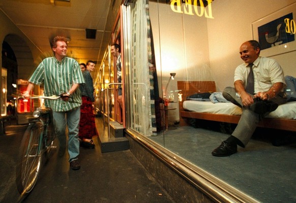 Ueli Maurer, Parteipraesident der Schweizerischen Volkspartei (SVP), rechts, zieht sich am Montagabend, 22. Juni 1998, in Bern in seinem temporaeren Hotelzimmer - im Schaufenster des Warenhauses seine ...