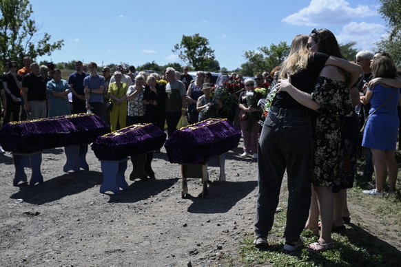 Relatives and friends mourn over coffins during a funeral ceremony for Mykyta and Sofia Lamekhov and their son Lev at a cemetery in Sloviansk, on August 5, 2025, amid the Russian invasion of Ukraine.