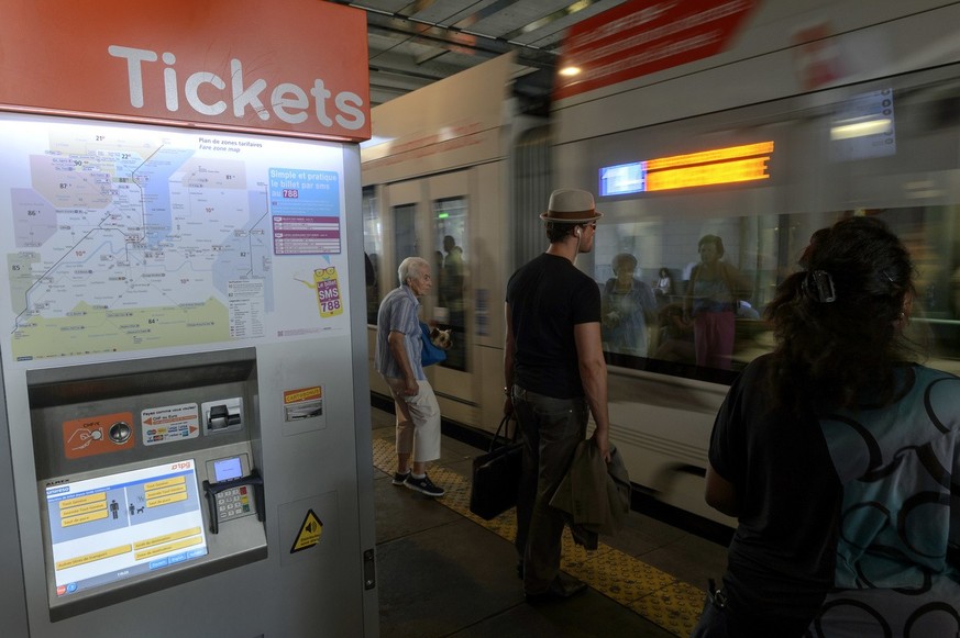 Un distributeur de billets des Transports Publics Genevois (TPG) photographie, devant des personnes qui attendent un tram, ce jeudi 16 juillet 2015 a Geneve. Depuis 150 ans, les Transports publics gen ...