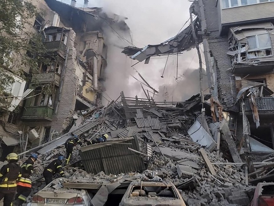 A handout photo released by the press service of the State Emergency Service of Ukraine shows Ukrainian rescuers working at the site of a damaged residential building after shelling in the city of Zap ...