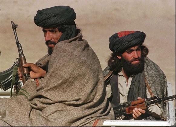 Two Taliban fighters sit in the back of their vehicle as they wait for orders at a front line position some 20 kilometers (13 miles) north of Kabul Saturday, October 26, 1996. This area was mainly qui ...