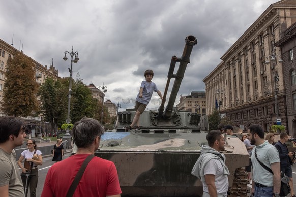 epa10130455 A boy stands on a Russian armored military vehicle that was damaged in fights with the Ukrainian army, displayed on Khreshchatyk street, in downtown Kyiv, ahead of the &#039;Independence D ...