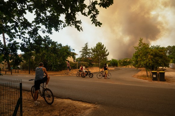 People watch massive plumes of smoke caused by wildfires in Le Porge, western France, Thursday, July 23, 2026. (AP Photo/Caroline Blumberg)
France Extreme Weather Heat