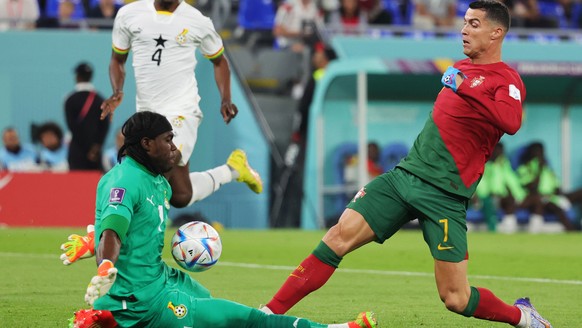 epa10325424 Cristiano Ronaldo (R) of Portugal in action against goalkeeper Lawrence Ati-Zigi of Ghana during the FIFA World Cup 2022 group H soccer match between Portugal and Ghana at Stadium 947 in D ...