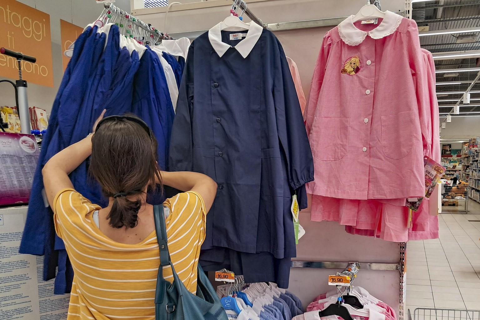 epa11559974 A woman looks at children&#039;s clothing at a store offering school supplies for the first day back to school including notebooks, pencil cases, backpacks, pencils, and pens, in Rome, Ita ...