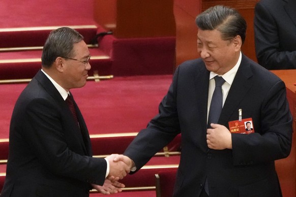 Newly elected Premier Li Qiang, left, shakes hands with Chinese President Xi Jinping during a session of China&#039;s National People&#039;s Congress (NPC) at the Great Hall of the People in Beijing,  ...