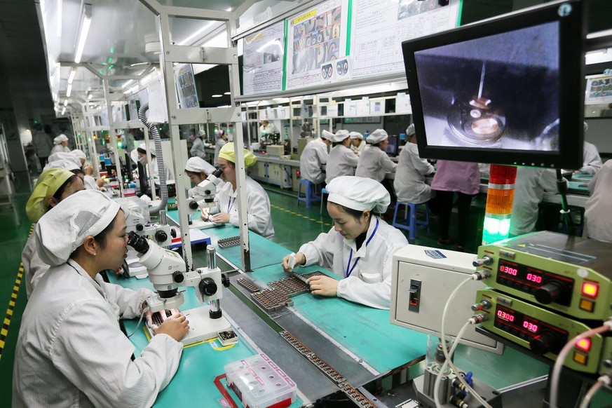 epa05857345 Women workers use microscopes to assemble micro motors for phones at a factory in Huaibei, Anhui province, central China, 07 March 2017 (issued 19 March 2017). China will not launch new po ...