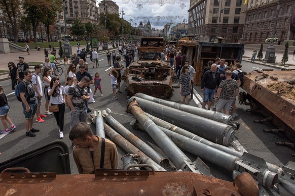 epa10130433 People look at Russian armoured military vehicles and items that were destroyed in fights with the Ukrainian army, displayed on Khreshchatyk street, in downtown Kyiv, ahead of the 'In ...