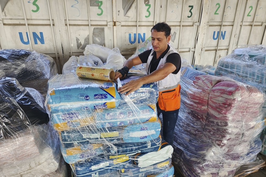 FILE - United Nations and Red Crescent workers prepare the aid for distribution to Palestinians at UNRWA warehouse in Deir Al-Balah, Gaza Strip, on Monday, Oct. 23, 2023. (AP Photo/Hassan Eslaiah, Fil ...