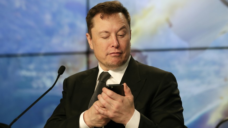 FILE - Elon Musk founder, CEO, and chief engineer/designer of SpaceX jokes with reporters as he pretends to search for an answer to a question on a cell phone during a news conference after a Falcon 9 ...