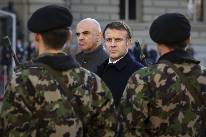 French President Emmanuel Macron, right, and Switzerland President Alain Berset, left, inspect the guard of honour of the Swiss army, on the Federal square in front of the Federal Palace, the Swiss Pa ...