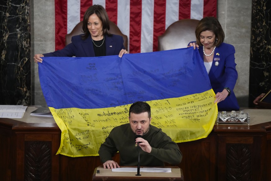 Vice President Kamala Harris and House Speaker Nancy Pelosi of Calif., right, react as Ukrainian President Volodymyr Zelenskyy presents lawmakers with a Ukrainian flag autographed by front-line troops ...