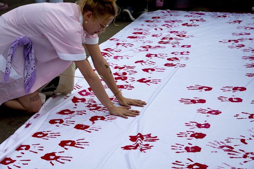 Une femme pose ses empreintes de mains peintent en rouge sur un drap blanc lors du rassemblement &quot;Mon corps, mon choix!&quot; qui a eu lieu ce mardi, 28 juin 2022, sur la Place des Nations a Gene ...