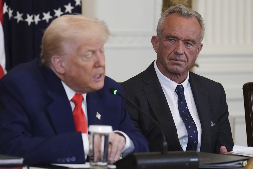 FILE - President Donald Trump, left, speaks as Health and Human Services Secretary Robert F. Kennedy Jr. listens during a Make America Healthy Again (MAHA) Commission Event in the East Room of the Whi ...
