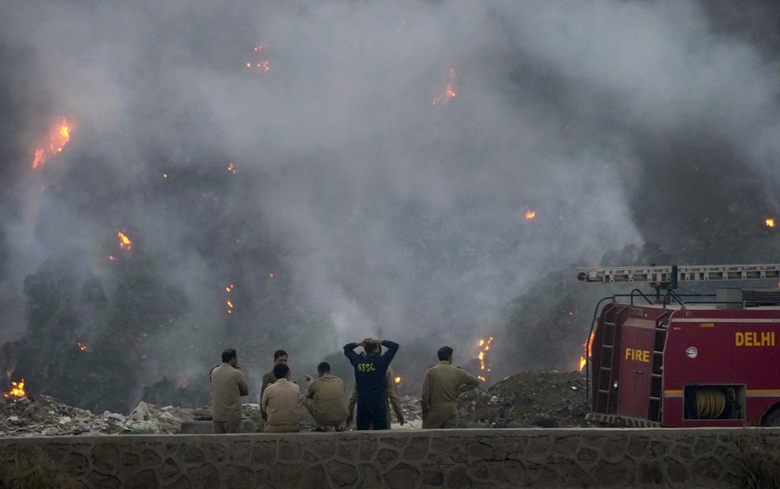 Fire officials assess a raging fire at the Bhalswa landfill in New Delhi, India, Wednesday, April 27, 2022. The landfill that covers an area bigger than 50 football fields, with a pile taller than a 1 ...