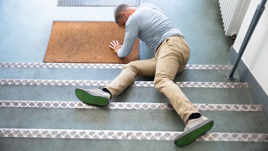 Mature Man Lying On Staircase After Slip And Fall Accident