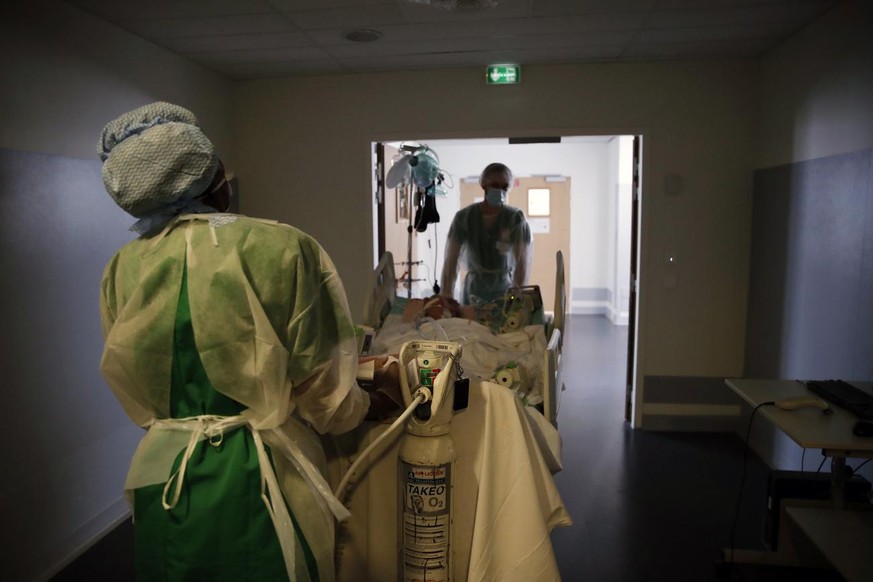 Medical workers move a patient affected with the COVID-19 for a checking scanner in the Amiens Picardie hospital Tuesday, March 30, 2021 in Amiens, 160 km (100 miles) north of Paris. France is now fac ...