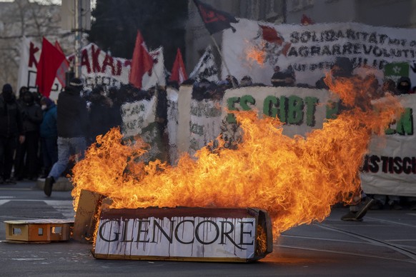 Vermummte Teilnehmer einer unbewilligten Klimadenonstration zuenden einen Kartonturm mit Firmennamen an in Basel, am Samstag, 11. Februar 2023. (KEYSTONE/Georgios Kefalas)