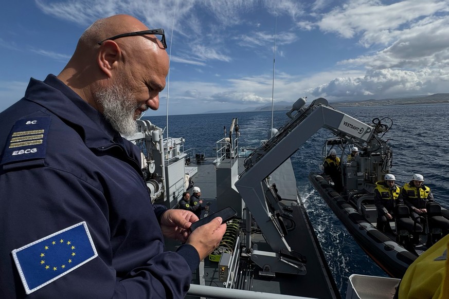 Frontex Contingent Commander Georgios Pyliaros takes pictures of Frontex officers from the Guardia di Finanza OPV Osum as they prepare in their speedboat to be lowered into the sea during a patrol in  ...