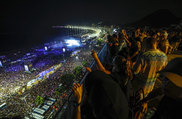 epa12929276 People watch Colombian singer Shakira perform during a concert from a terrace overlooking Copacabana Beach in Rio de Janeiro, Brazil, 02 May 2026. Shakira headlined a free concert on the b ...