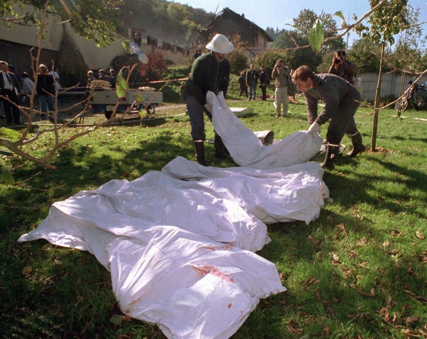 EDITORS NOTE : GRAPHIC CONTENT - Policmen carry dead bodies out of a farm in Cheiry, Canton of Fribourg, Switzerland, Wednesday, October 5, 1994. At least 48 people, including children, were found dea ...