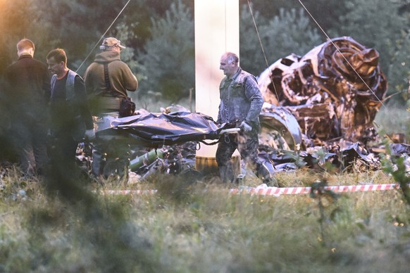 People carry a body bag away from the wreckage of a crashed private jet, near the village of Kuzhenkino, Tver region, Russia, Thursday, Aug. 24, 2023. Russian mercenary leader Yevgeny Prigozhin, the f ...
